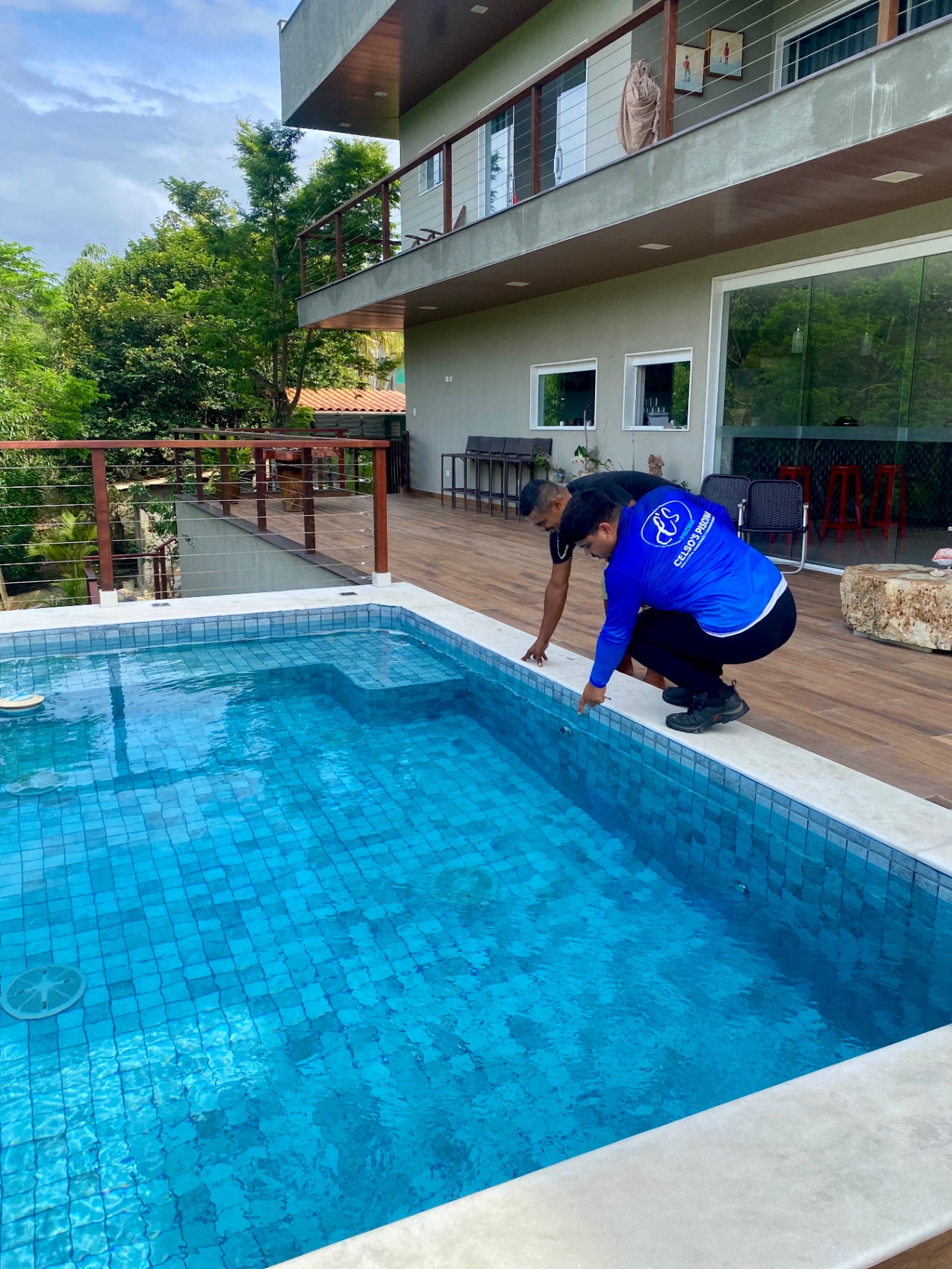 Profissional da Celso's Piscinas apontando detalhes da piscina ao lado do cliente